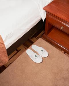 瓦拉斯El Tumi Hotel的睡床旁边的地板上一双白色拖鞋