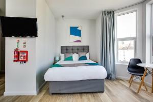 大雅茅斯OYO Studiotel GY - Modern Hotel Apartments的一间卧室配有一张床,墙上配有电视