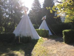 NonceveuxArkeo - Luxury tents and cabins at the river的两顶白色帐篷,位于一个树木繁茂的院子内