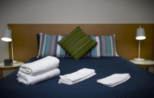 达尔文Darwin City Suites with Harbour View的一张蓝色的床,上面有毛巾,还有两盏灯