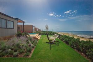 梅杜林Arena Grand Kazela Camping Homes的坐在海滩附近的草地上的长凳