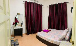 哥打巴鲁Nurul Amin Guest House Pantai Cahaya Bulan Kota Bharu的一间卧室配有红色窗帘、一张床和镜子