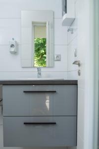 赫维兹Twins Apartman Hévíz的白色的浴室设有水槽和镜子
