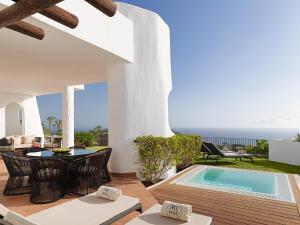 吉亚德伊索拉Las Terrazas de Abama Suites的庭院设有游泳池、桌子和椅子。