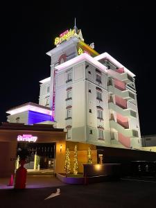 岐阜ホテルバースデー岐阜西店 HOTEL Birthday GifuWest的一座白色的大建筑,上面有 ⁇ 虹灯标志