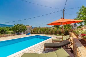 希洛Holiday house Villa Šilo的游泳池旁的游泳池配有遮阳伞和椅子