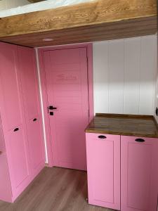 博阿齐奇Lavira Tiny House Village的粉红色的厨房配有白色的橱柜和木制天花板