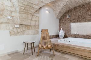 奥斯图尼Alba Luxury Suite的带浴缸和木椅的浴室