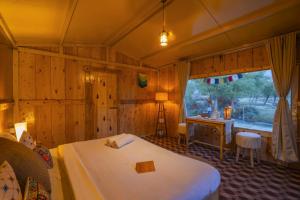 列城Bikamp Camp Leh Ladakh的一间卧室设有两张床、一张桌子和一个窗口。