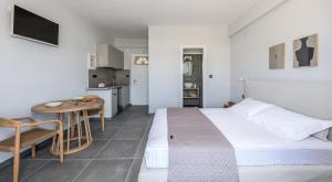 阿达玛斯宜普卡普斯一室公寓酒店的一间卧室配有一张床铺和一张桌子,还设有一间厨房