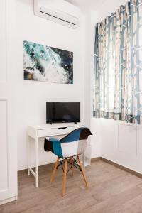 墨西拿Blue Apartment Messina的客房设有书桌、电视和椅子。