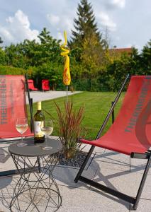 塔亚河畔拉镇Appartementhaus Thermeneck的一张桌子、两把椅子和一瓶葡萄酒
