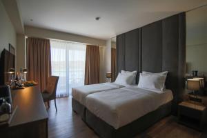 韦莱斯Glorius Hotel的酒店客房设有一张大床和一张书桌。