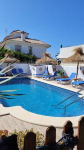 洛斯卡尼奥斯德梅卡Hostal Casa Arco Iris (Playa)的一个带椅子和遮阳伞的大型游泳池