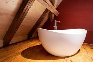SchlossruedResort Schloss Rued的浴室铺有木地板,配有白色浴缸。