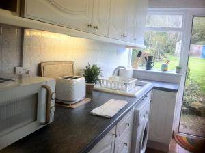 蒙默思Charming cottage within farmhouse的厨房配有白色橱柜和带烤面包机的台面。