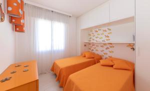利多迪耶索罗Magnifico appartamento Dominique Jesolo Lido Carraro Immobiliare - Family Apartments的配有橙色床单的客房内的两张床