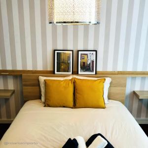 波尔图rosario inn porto的一张带黄色枕头的床和墙上的两张照片