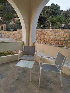 奇亚Villa Bianca的庭院设有两把椅子和桌子,还有石墙