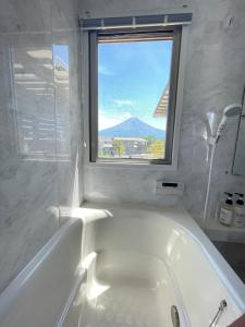 富士河口湖Necoana Glamping的带窗户的浴室内的白色浴缸