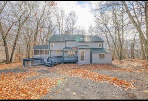 迈阿密Cabin at poconos,spa-room with Hot tub, grill, fire pit的树林里大房子,地上有树叶