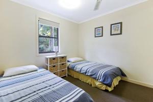 天阁露玛Villa 30 Tangalooma的一间卧室设有两张床和窗户。