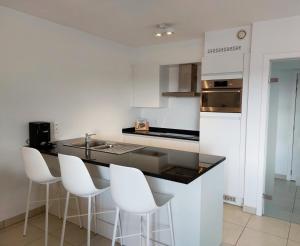 尼乌波特Duplex Villa Capricia appartement met zwembad Nieuwpoort Jachthaven的厨房配有白色橱柜和黑色台面