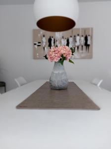 尼乌波特Duplex Villa Capricia appartement met zwembad Nieuwpoort Jachthaven的花瓶,花朵粉红色,坐在桌子上