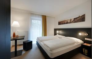 罗登戈Hotel Tirolerhof的卧室配有一张白色大床和一张书桌