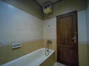 丹戎Hotel Indiana Syariah Mitra RedDoorz的带浴缸的浴室和木门。