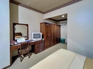 丹戎Hotel Indiana Syariah Mitra RedDoorz的一间卧室配有一张桌子、一台电视和一面镜子