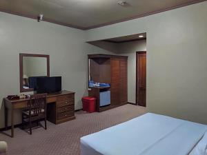 丹戎Hotel Indiana Syariah Mitra RedDoorz的一间卧室配有一张床、一张书桌和一台电视