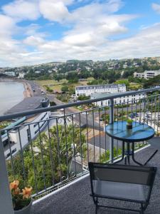 托基Loveliest Homes Torquay - 3 bed, 2 bathroom, balcony, parking的阳台配有桌子,享有海滩美景