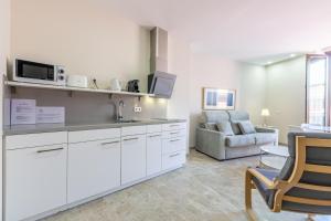 塞维利亚奥拓圣克鲁斯绿色公寓的一间带白色橱柜的厨房和一间带沙发的客厅