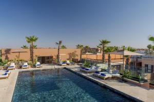 马拉喀什Pestana CR7 Marrakech的度假村内带躺椅和椅子的游泳池