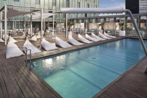 巴塞罗那美利亚巴塞罗那天空四星级酒店的大楼内带白色椅子的大型游泳池