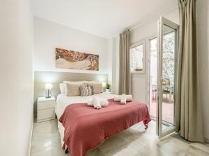 塞维利亚圣马科斯公寓式酒店的白色卧室配有一张带红色毯子的大床