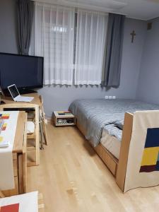 首尔Gyeongbokgung Palace Seochon Christian Home - Foreigner Only的一间卧室配有一张床、一张书桌和一台电视