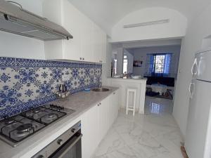 古莱比耶Maison S+1 très bien équipée à 2mn de la plage的厨房配有白色橱柜和蓝色及白色瓷砖