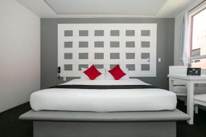 帕丘卡德索托Hotel Euro Confort,Pachuca的卧室配有带红色枕头的大型白色床