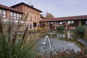 SandiglianoRELAIS CASCINA ERA的一座带喷泉的砖砌建筑前的池塘