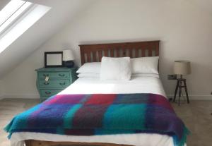 GortahorkThe Birdhouse with Hot Tub的一间卧室配有一张带彩色毯子的床