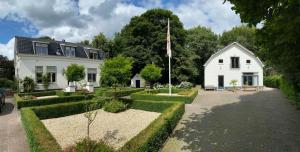 TynaarloKoetshuys van Villadelfia的院子里有旗帜的白色房子