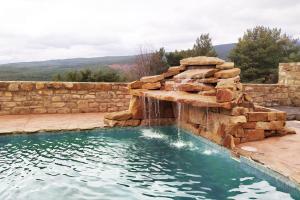 金塔纳尔德拉谢拉Camino del Pinar的一个带瀑布和石墙的游泳池