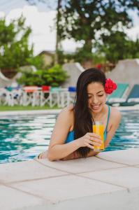马拉圭Rioma Hotel的游泳池里的女孩喝一杯