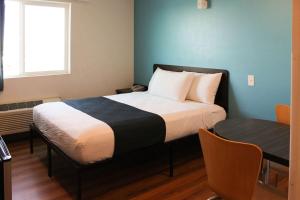 雷克斯堡Motel 6 Rexburg, ID的一间卧室配有一张带桌子和窗户的床