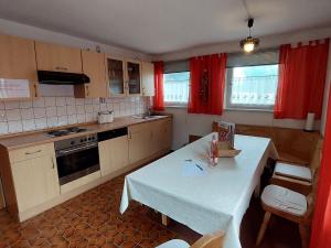 诺伊赖歇瑙Spacious holiday home in Neureichenau Schimmelbach的厨房配有白色的桌子和红色的窗帘