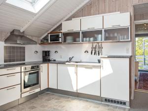 罗莫柯克比6 person holiday home in R m的厨房配有白色橱柜和炉灶。