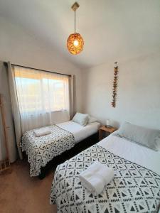 CatapilcoEco Parcela La Chacra的一间卧室设有两张床、一个窗户和一个吊灯。