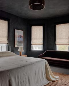 布拉德利比奇The James Bradley的一间卧室配有一张床、一张沙发和窗户。